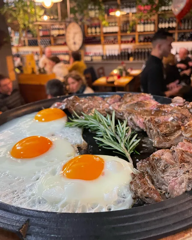 Tagliata con uova al tegamino servita in sala, con gli ospiti a tavola sullo sfondo – La Piazzetta, Verona