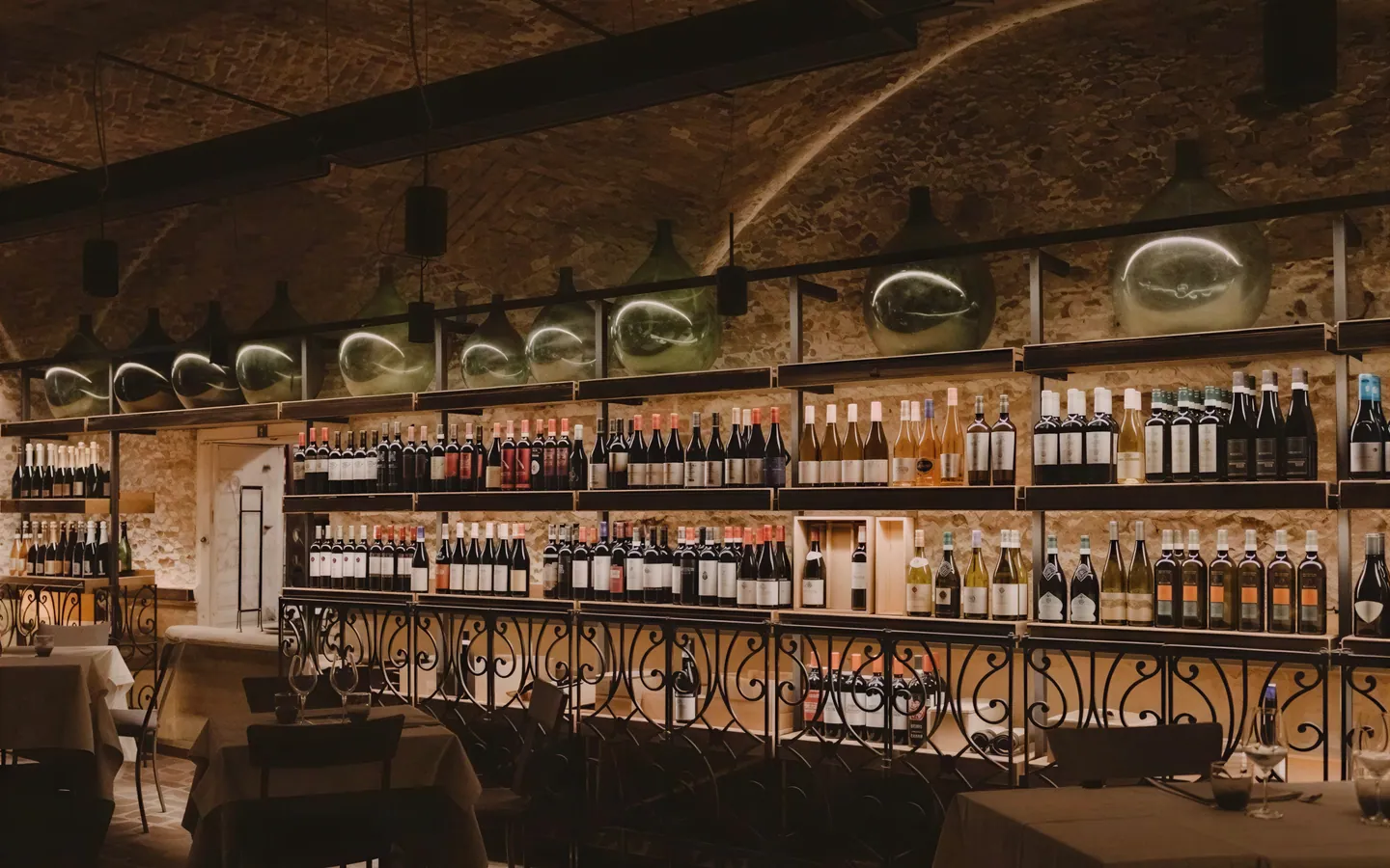 La parete dei vini della Piazzetta, con le bottiglie illuminate e la ringhiera in ferro battuto – Verona